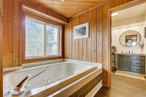 y baño con bañera y paredes de madera. en Family Dreams Condo at Lighthouse Cove en Wisconsin Dells