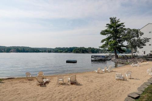 a beach with lounge chairs and a boat in the water at Family Dreams Condo at Lighthouse Cove in Wisconsin Dells
