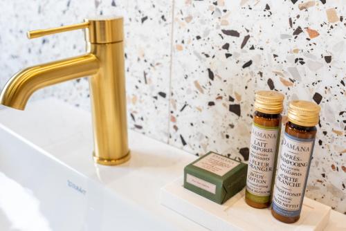 dos botellas de aceites esenciales sentadas en un mostrador de baño junto a un fregadero en Queens Boutique Hotel, en París