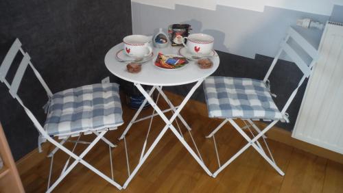 - une petite table blanche avec deux chaises et des tasses à thé dans l'établissement Grande chambre SDB privée avec balcon, à Lannion