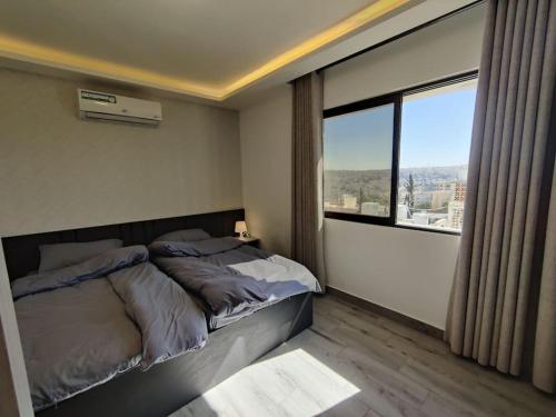 een slaapkamer met een bed en een groot raam bij (42)m luxury room in Ash Shumaysānī