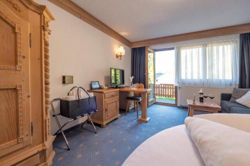a hotel room with a bed and a desk with a television at Hotel Bergkristall in Silbertal