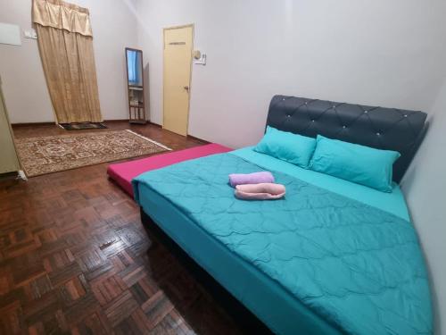 1 dormitorio con 1 cama azul y 2 toallas en D’Lestari Homestay en Seri Kembangan