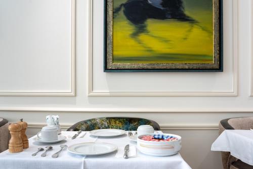 a table with plates and a painting on the wall at Queens Boutique Hotel in Paris