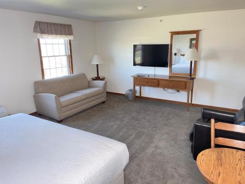 a hotel room with a bed and a couch and a television at Farmstead Inn and Conference Center in Shipshewana