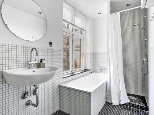 Sanders Stage - Perfectly Planned Three-Bedroom Apartment Near Nyhavn في كوبنهاغن: حمام مع حوض وحوض ومرآة