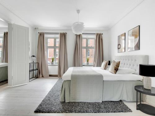 Sanders Stage - Perfectly Planned Three-Bedroom Apartment Near Nyhavn في كوبنهاغن: غرفة نوم بيضاء مع سرير كبير وحوض استحمام
