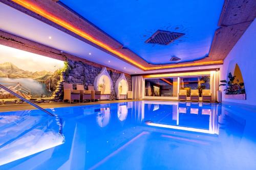 an indoor pool in a hotel with blue lighting at Hotel Bergkristall in Silbertal