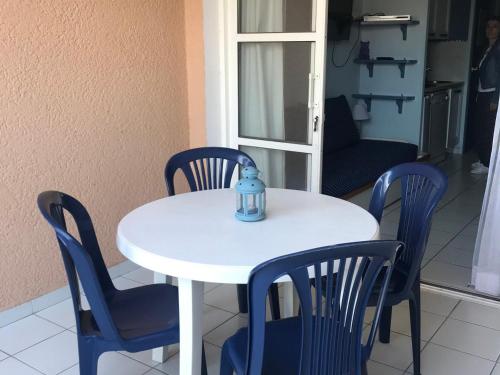 - une table et des chaises blanches avec une bouteille dans l'établissement Studio 4 pers, terrasse couverte, piscine et parking, Cap Esterel - FR-1-504-653, à Saint-Raphaël