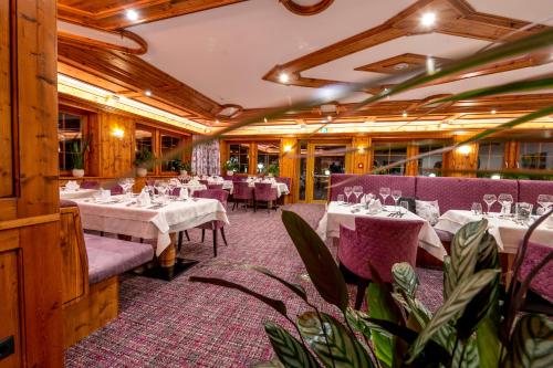 a restaurant with white tables and purple chairs at Hotel Bergkristall in Silbertal