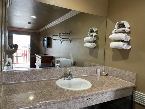 a bathroom with a sink and a mirror and towels at Hiland Motel in Long Beach