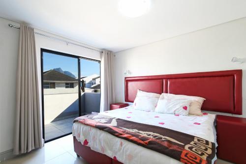 a bedroom with a red bed and a sliding glass door at Camdene Guesthouse in Cape Town