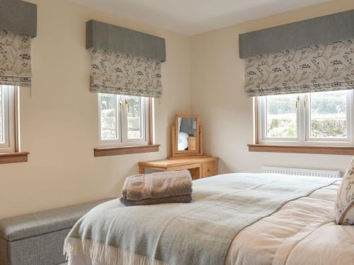 a bedroom with a large bed with two windows at The Lodge in Linlithgow