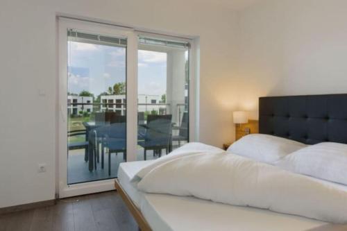 1 dormitorio con 1 cama y balcón con mesa en LUXUS Appartement am Golfplatz und Therme Lutzmannsburg, en Zsira