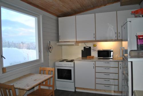 a kitchen with white cabinets and a table and a window at Skoghus in Silsand