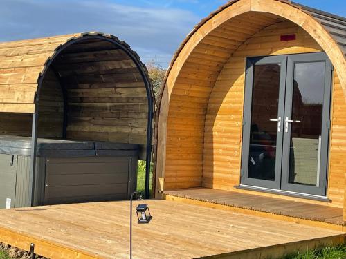 two arched doors on a house with a wooden deck at Little Meadow Pods with Hot Tub in York