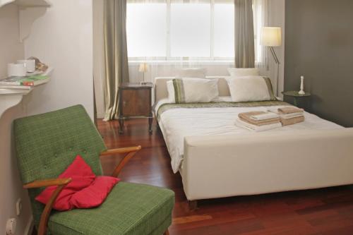 sypialnia z białym łóżkiem i zielonym krzesłem w obiekcie Apartamento Independente Praia & Porto - Limpo e Seguro w mieście Matosinhos