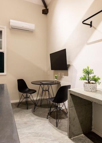 a dining room with a table and chairs and a tv at ZEST Pedroso in Sao Paulo
