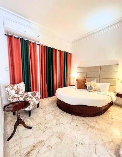 a bedroom with two beds and a chair and curtains at Jamaica Palace Hotel in Port Antonio