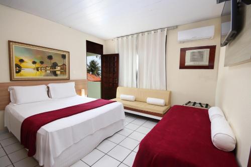 a hotel room with a bed and a couch at Pousada Shalom Beach in Maragogi