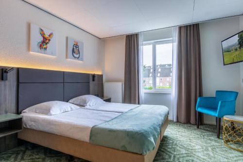 um quarto de hotel com uma cama e uma cadeira azul em Hotel Edenpark em Brunssum