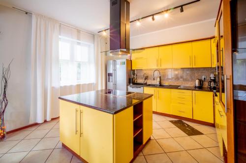a yellow kitchen with yellow cabinets and a refrigerator at Dom na Mazurach LUNA HAUS in Ełk