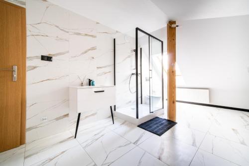 a bathroom with a shower and a white wall at Dom na Mazurach LUNA HAUS in Ełk