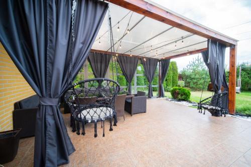 a patio with black curtains and a table and chairs at Dom na Mazurach LUNA HAUS in Ełk