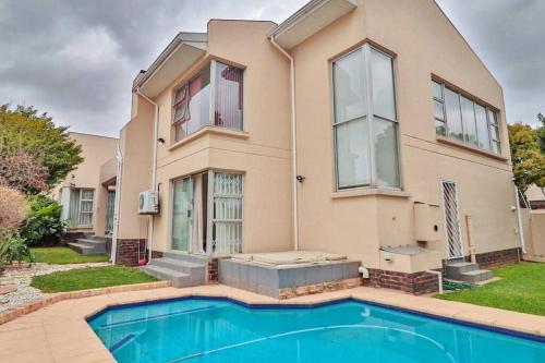 a house with a swimming pool in front of it at Luxurious Pvt Apartment ,Power backup, Jaccuzi & Pool in Sandton