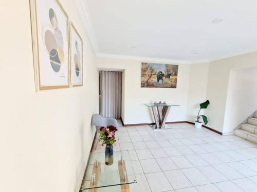 a living room with a vase of flowers on a glass table at Luxurious Pvt Apartment , Pool, Jaccuzi & Aircons in Sandton