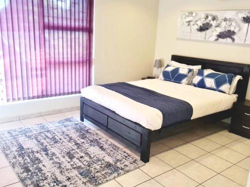 a bedroom with a bed with blue and white pillows at Luxurious Pvt Apartment ,Power backup, Jaccuzi & Pool in Sandton