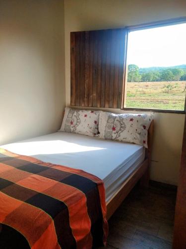a small bedroom with a bed with a window at Chácara Recanto da Paz in Pirenópolis