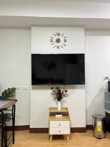 a living room with a tv and a vase of flowers at Cozy Mesaverte Condo Residences in Cagayan de Oro