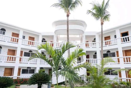 a white building with palm trees in front of it at Ocean Palms - 1Bed 1Bth King Suite Condo in Cabarete