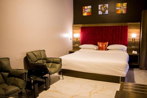 a hotel room with a bed and two chairs at Hotel Horizon Entebbe in Entebbe