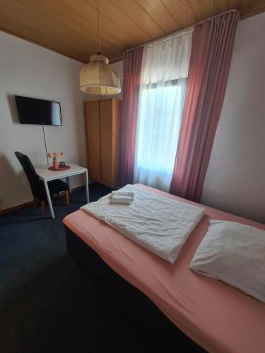 a bedroom with a bed and a desk and a window at Hotel Dalmacija in Mayen