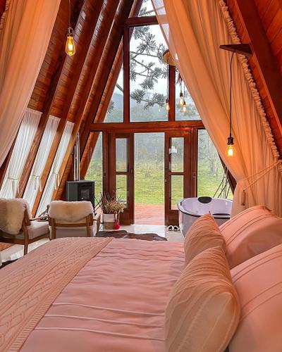 a bedroom with a bed and a large window at Pousada Maçã Araucária in São Joaquim