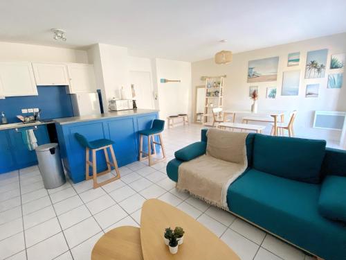 a living room with a blue couch and a kitchen at Le Pontappart in Royan