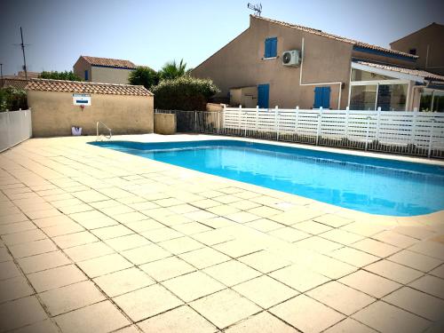 une piscine devant une maison dans l'établissement De la Clape à la mer mon petit pavillon labellisé - f2- piscine commune - wifi gratuit- parking privé - arrivee autonome - 800 m plage - grande terrasse abritée vent -, à Saint Pierre La Mer