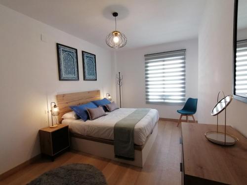 una camera con un grande letto e una sedia blu di Relax & home, apartamento con terraza y parking a La Zubia