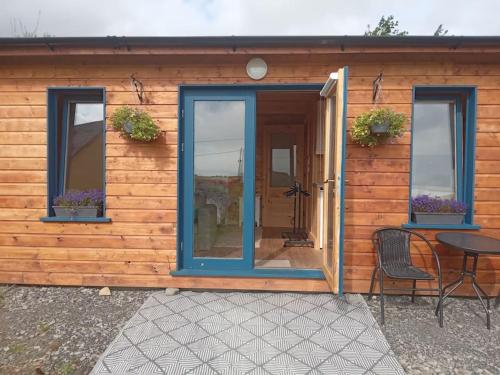 a wooden house with a blue door and a table at Ceaser's cabin is a cosy 1 bedroom cabin in Lahinch