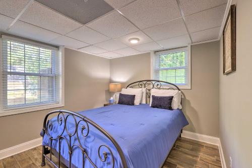 a blue bed in a bedroom with two windows at 21 Mi to Atlanta Getaway with Fire Pit! in Jonesboro