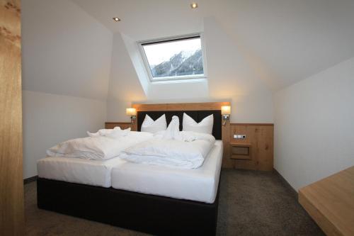 a bedroom with a bed with white sheets and a window at Relax Apartments in Ischgl