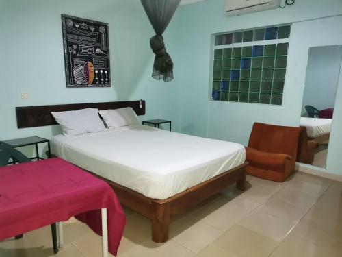 een slaapkamer met een wit bed en een stoel bij HOTEL BADINCA Alojamento Low Cost in Bissau avenida FRANCISCO MENDES in Bissau