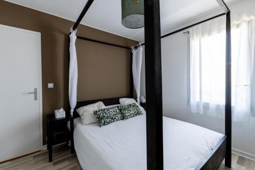 um quarto com uma cama de dossel e uma janela em Maison familiale avec piscine em Mauguio