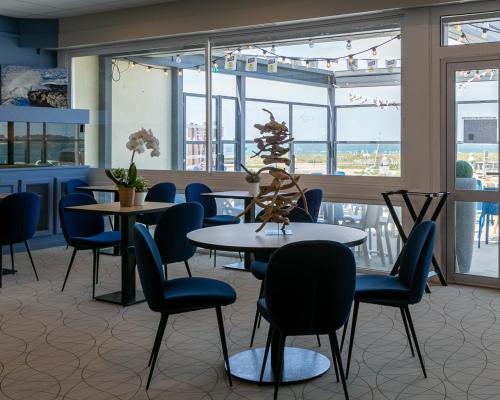 a dining room with tables and chairs and windows at Logis Hôtel Le Calluna Restaurant La Flottille in Préfailles