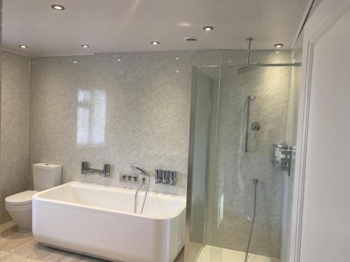 a bathroom with a tub and a shower and a toilet at PRIVATE•ASTONISHING•CONTRACTOR•DETACHED•LutonAirport•WI-FI•PARKING•SPACIOUSNESS in Luton
