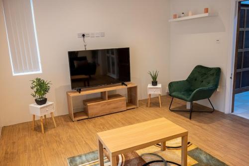 ein Wohnzimmer mit einem Flachbild-TV und einem grünen Stuhl in der Unterkunft PRIVATE•ASTONISHING•CONTRACTOR•DETACHED•LutonAirport•WI-FI•PARKING•SPACIOUSNESS in Luton