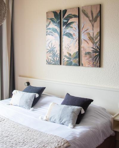 a bedroom with a bed with three paintings on the wall at Logis Hôtel Le Calluna Restaurant La Flottille in Préfailles