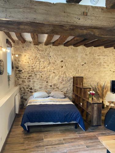 a bedroom with a bed and a stone wall at Studio Manhattan WIFI Plein de charme in Gien